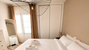 A hotel room with a large bed, a bedside table, a lamp, a mirror, and a wardrobe. - Appartement Villalia  (Puerto del Carmen)