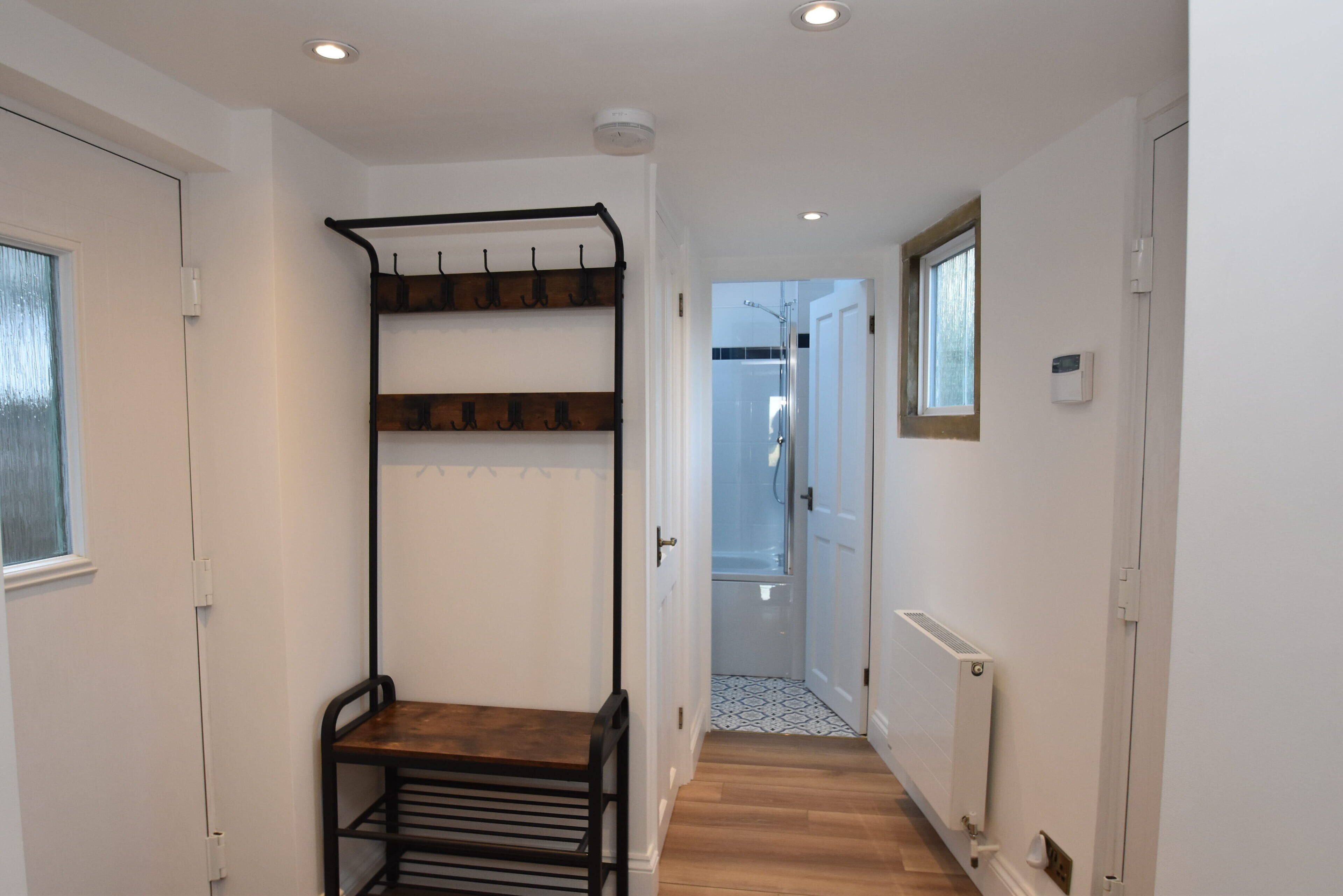 A narrow hallway with a wooden bench, a coat rack, and a radiator.