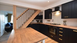 Une cuisine moderne avec des meubles de couleur sombre, un escalier en bois et un îlot central.