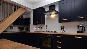 Une cuisine moderne avec des meubles de couleur sombre, un escalier en bois et un four encastré.