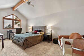 A bedroom with a bed, bedside tables, a chair, a desk, and a window.