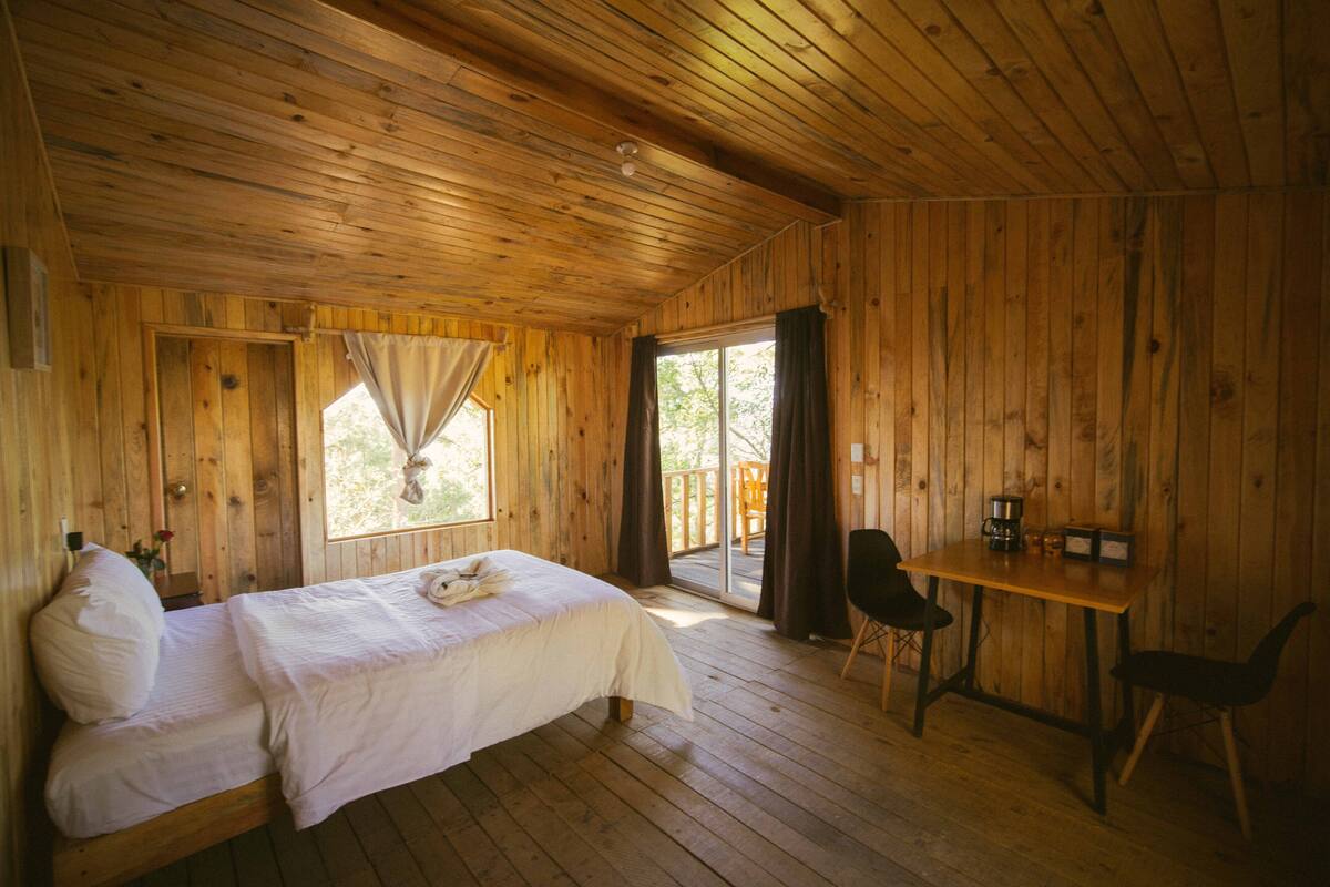 Une pièce dans un chalet en bois, comprenant un lit, une table et une chaise.