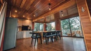 A wooden interior with a kitchen, dining area, and large windows. - Cabañas Rancho Viejo (San Mateo Río Hondo)