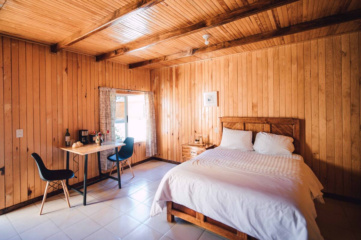 Une pièce en bois avec un lit, un bureau et une chaise.