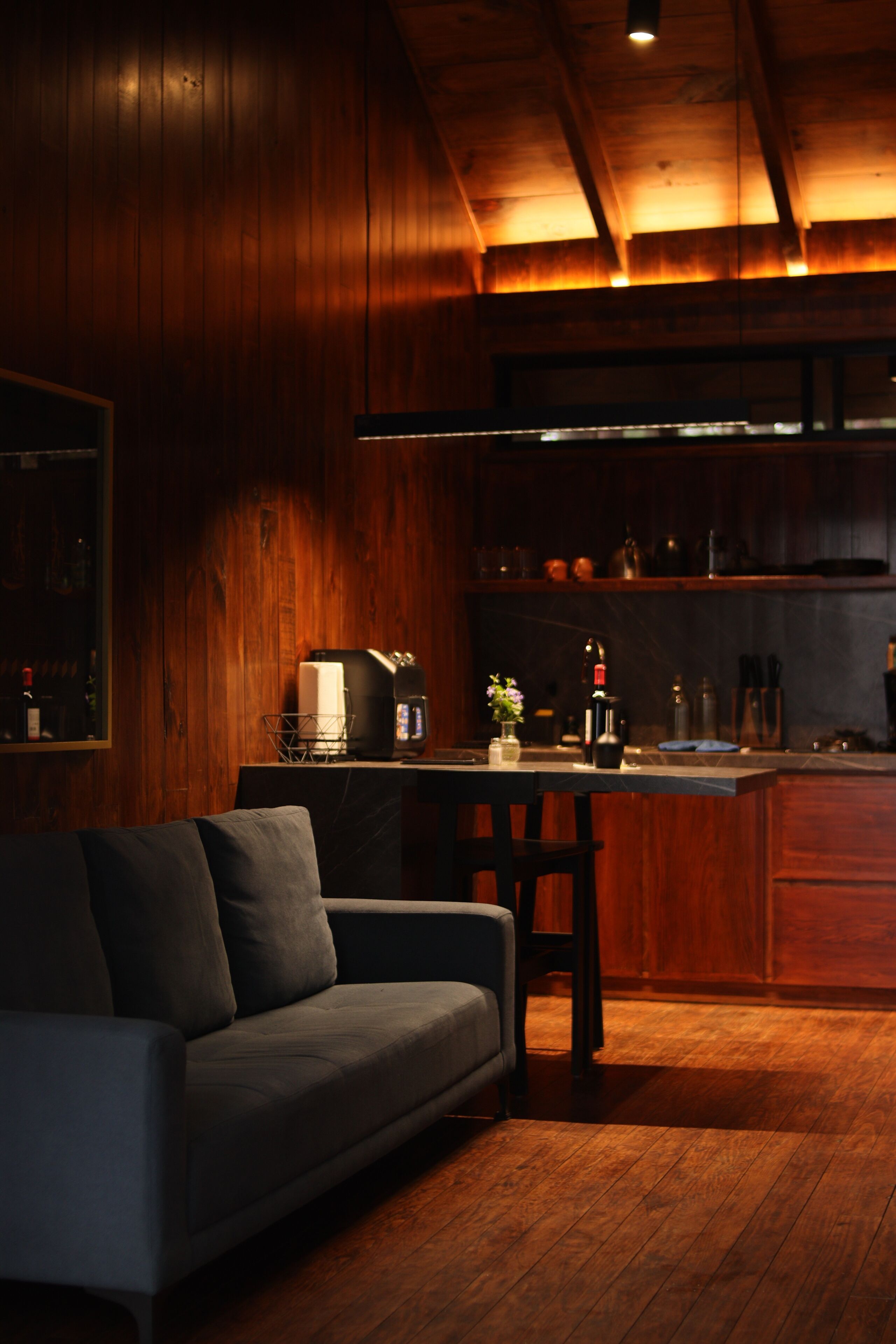Un salon confortable avec un canapé, une table basse et un coin cuisine doté de meubles en bois et d’un plan de travail.