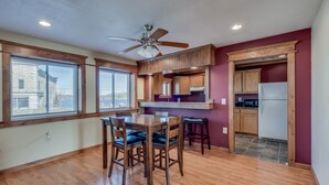 A dining area with a wooden table and chairs, a ceiling fan, and a kitchen area with wooden cabinets and a refrigerator. - Riverview Townhouse I in Downtown Alexandria Bay (Alexandria Bay)