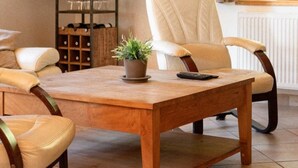 Een gezellige woonkamer met een houten salontafel, twee leren fauteuils, een potplant en een wanddecoratie van een opgezet hert.