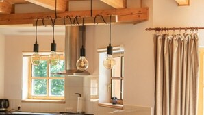 Een moderne keuken met houten balken, hanglampen en een eethoek met bruine stoelen.