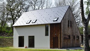 Una moderna casa a due piani con tetto spiovente, ampie finestre e rivestimento in legno.
