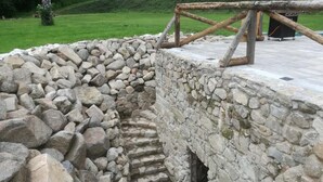 Una costruzione in pietra con una scala di legno che conduce a un'area simile a una grotta.