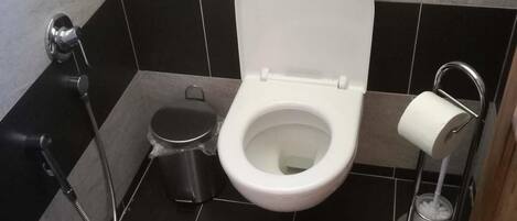 Un baño moderno con inodoro, bidé y secador de manos.