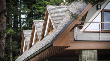 A modern house with a sloped roof, wooden beams, and stone pillars.