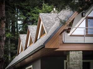 A modern house with a sloped roof, wooden beams, and stone pillars.