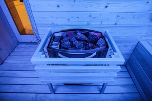 A metal fire pit with charcoal on a wooden deck.
