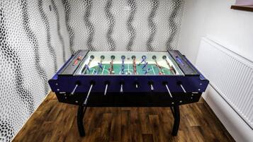 Una mesa de fútbol de mesa en una habitación con suelo de madera y pared blanca con textura.