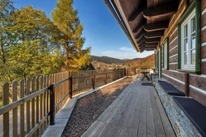 A wooden deck with a railing, a bench, and a building with windows.