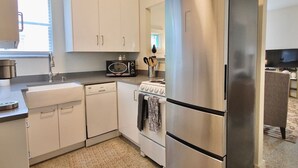 A modern kitchen with white cabinets, a stainless steel refrigerator, a microwave, and a stove. - Lakeside - Lake Davis Art Deco Cottage 5C (Orlando)