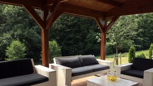 An outdoor patio with wooden furniture, including sofas and tables, under a wooden pergola. - Villa Pool Stupna Ksa450 (Vidochov)