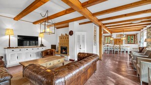 A spacious living area with a fireplace, wooden beams, a television, and a dining area with chairs. - Villa Pool Stupna Ksa450 (Vidochov)