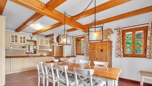 A spacious kitchen with wooden beams, a dining table with chairs, and a large wooden cabinet. - Villa Pool Stupna Ksa450 (Vidochov)