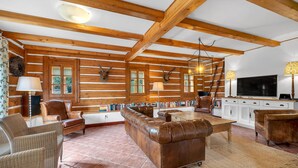 A spacious living room with wooden beams, leather sofas, a fireplace, and a television. - Villa Pool Stupna Ksa450 (Vidochov)