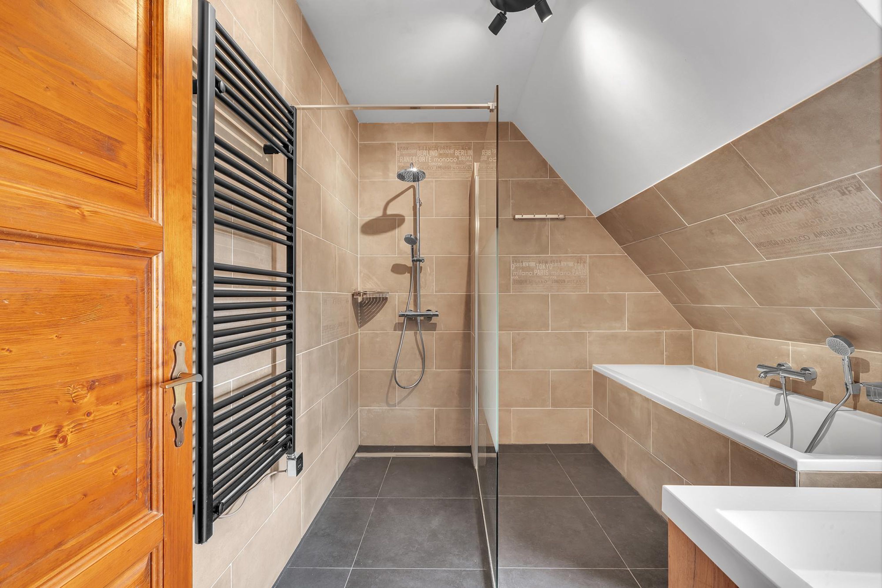 Un baño moderno con ducha, bañera y puerta de madera.