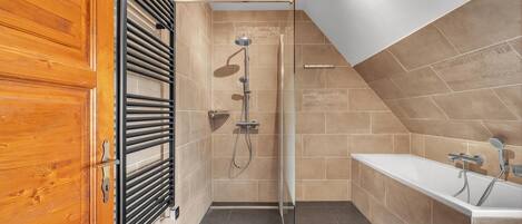Un baño moderno con ducha, bañera y puerta de madera.