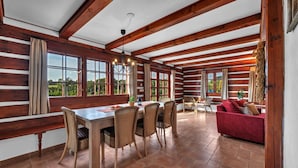 A rustic wooden interior with a dining area, red sofa, and large windows offering a view of greenery. - Villa Pool Stupna Ksf095 (Vidochov)