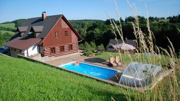 A house with a swimming pool, surrounded by a lush green landscape.