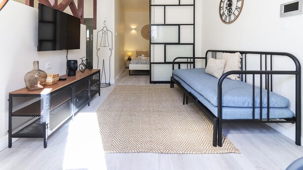 A modern bedroom with a bed, a TV, a dresser, and a decorative wall clock.
