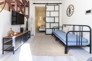 Une chambre à coucher moderne, comprenant un lit, un téléviseur, une commode et une horloge murale décorative.