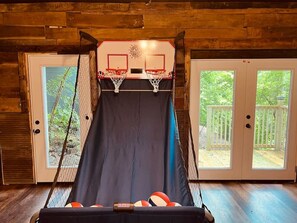 Ein Basketballkorb mit Netz, zwei Glastüren und Blick auf eine Holzterrasse.