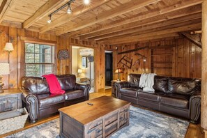 A wooden interior with leather sofas, a wooden coffee table, and a rustic ambiance. - Whiskey Ridge Lodge ~ Rustic Luxe Cabin with Hot Tub, Game Lounge & Epic Mountain Views (Gatlinburg)