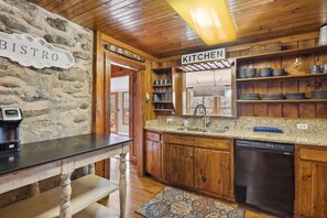 A rustic kitchen with wooden cabinets, granite countertops, and a coffee machine. - Whiskey Ridge Lodge ~ Rustic Luxe Cabin with Hot Tub, Game Lounge & Epic Mountain Views (Gatlinburg)