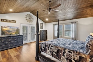 A bedroom with a four-poster bed, a ceiling fan, a TV on a dresser, and a sign that reads "DO NOT FEED THE BEARS".