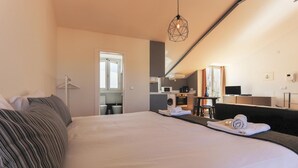 Habitación de hotel con una cama grande, una kitchenette pequeña, un espejo y vistas a la ciudad.