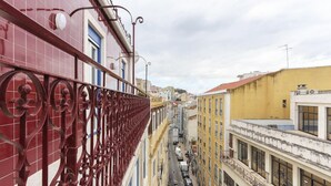 Uma rua estreita ladeada por edifícios, com varandas e grades.