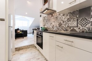 A modern kitchen with white cabinetry, a black countertop, and patterned backsplash tiles.