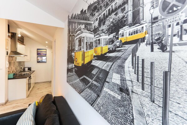 A modern living room with a large cityscape mural, a sofa, and a kitchen area.