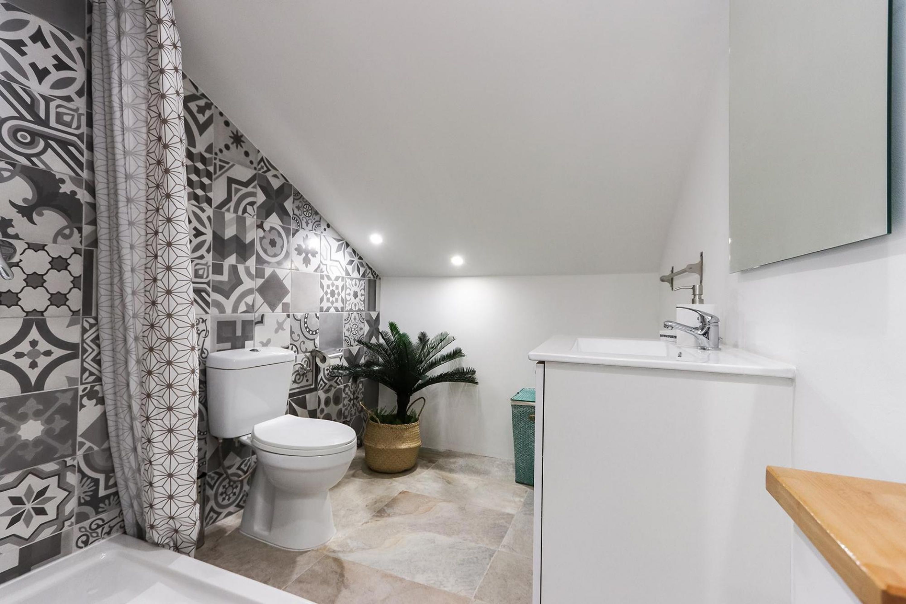 A bathroom with patterned tiles, a toilet, a sink, and a mirror.