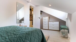 Een slaapkamer met een bed, een kledingkast, een spiegel en een deur naar een badkamer.