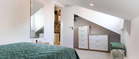 Un dormitorio con una cama, un armario, un espejo y una puerta que da a un baño.