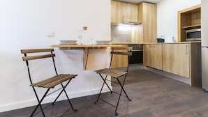 Une cuisine moderne avec des meubles en bois, un réfrigérateur en acier inoxydable et un petit coin bar avec des tabourets.
