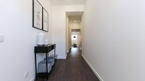 A narrow hallway with dark wooden flooring, white walls, and a black console table with storage baskets. - Benfica Apartments III by Homing (Lisbon)
