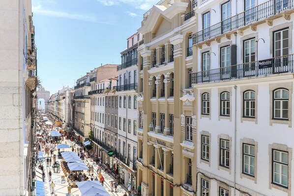 A street view of a historic building with multiple floors, balconies, and a row of shops on the ground floor. - Downtown Santa Justa by Homing (Lisbon)