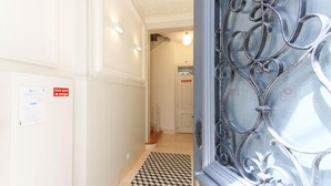 Un pasillo con piso a cuadros, un letrero de corte general de energía y una puerta metálica decorativa.