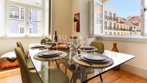 Mesa de comedor para cuatro con vistas a edificios a través de amplios ventanales.