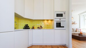 Una cocina compacta con armarios blancos, microondas y horno empotrado.