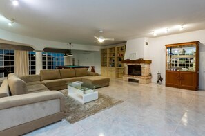 A spacious living room with a beige sofa, a glass coffee table, a fireplace, and a bookshelf. - Quintinha da Balaia in Albufeira (Albufeira)