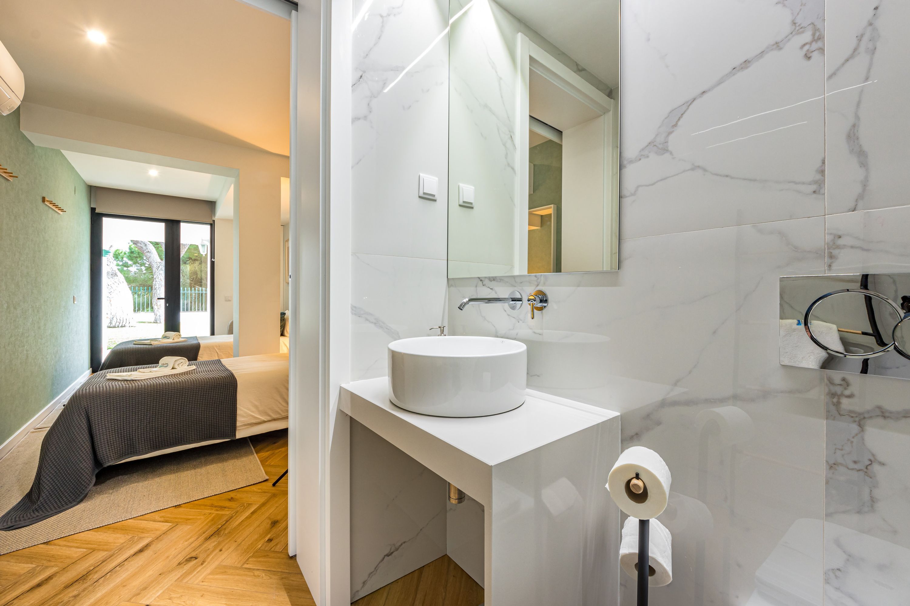 A modern bathroom with a marble sink, a large mirror, and a toilet paper holder.